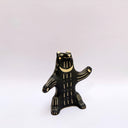 Ceramic sculpture of a black bear, sitting up on its hind legs, with cream colored sgraffito fur and texture lines.