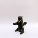 Ceramic sculpture of a black bear, sitting up on its hind legs, with cream colored sgraffito fur and texture lines.
