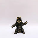 Ceramic sculpture of a black bear, sitting up on its hind legs, with cream colored sgraffito fur and texture lines.