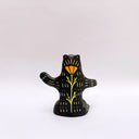 Ceramic sculpture of a black bear, sitting up on its hind legs, with cream colored sgraffito fur and texture lines.