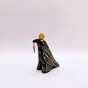 Ceramic sculpture of a black raven-like bird, with sgraffito line art, cream and red, on its feathers. It has a gold coin atop its head and a small key on a red string in its beak.