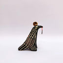 Ceramic sculpture of a black raven-like bird, with sgraffito line art, cream and red, on its feathers. It has a gold coin atop its head and a small key on a red string in its beak.