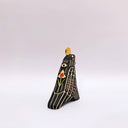 Ceramic sculpture of a black raven-like bird, with sgraffito line art, cream and red, on its feathers. It has a gold coin atop its head and a small key on a red string in its beak.