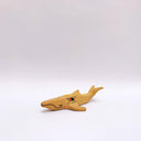 Small ceramic sculpture of a whale, with a long mouth and a circular 4-color emblem on the side of its body.