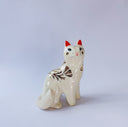 White ceramic figurine of a fox or cat with red ears and a gold leaf pattern on its body of poppy flowers and leaves.
