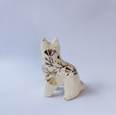 White ceramic figurine of a fox or cat with red ears and a gold leaf pattern on its body of poppy flowers and leaves.