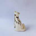 White ceramic figurine of a fox or cat with red ears and a gold leaf pattern on its body of poppy flowers and leaves.