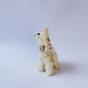 White ceramic figurine of a fox or cat with red ears and a gold leaf pattern on its body of poppy flowers and leaves.