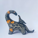 Ceramic sculpture of a black dinosaur with a long neck, looking to its own back which has a baby dinosaur standing on it. Both dinosaurs have a carved patterning of orange poppies with cream colored stylistic lines.