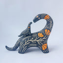 Ceramic sculpture of a black dinosaur with a long neck, looking to its own back which has a baby dinosaur standing on it. Both dinosaurs have a carved patterning of orange poppies with cream colored stylistic lines.