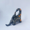 Ceramic sculpture of a black dinosaur with a long neck, looking to its own back which has a baby dinosaur standing on it. Both dinosaurs have a carved patterning of orange poppies with cream colored stylistic lines.