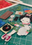 Illustration of a character laying on a red rug with a dog and listening to records.