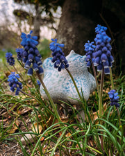 Ceramic sculpture of a character with a lumpy spotted body, tall thin legs, and small eyes and ears.