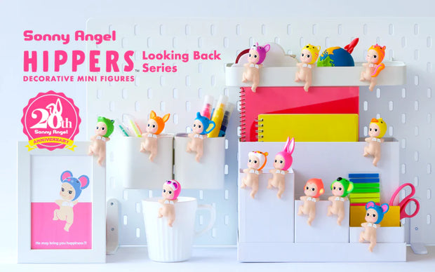 Vinyl figures of a Kewpie baby, nude aside from various animal shaped hood hat. It looks back over its shoulder with one leg hoisted up, as though climbing something.