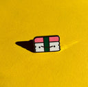 Enamel pin of a spam musubi with a simple cartoon smile.