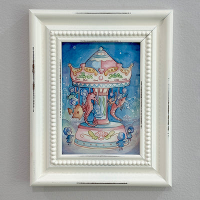 Framed artwork of a colorful carousel with seahorses and little shell children riding them on a gray wall.