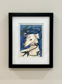 A stylized watercolor-style artwork of a white dog with dark blue birds and ribbon-like lines against a blue background. Piece is matted and inside a black frame.