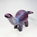 Purple and blue glossy ceramic sculpture of a long neck dinosaur with a simplistic, cute face.