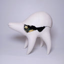 White ceramic sculpture of a quadruped creature with a large humped body, curved tall legs and a long neck. It has cracks running through its body and inside of it grows flowers. 