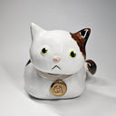 Ceramic cat-shaped sculpture with a gold tag on a white background