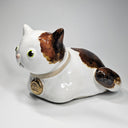 Ceramic cat-shaped sculpture with a gold tag on a white background