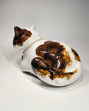 Ceramic cat-shaped sculpture with a gold tag on a white background