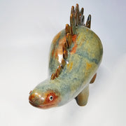 Glossy, multicolor ceramic sculpture of a dinosaur with many spikes on its long back like a stegosaurus. 