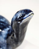 Close up of a sculpture of a sea monster akin to the Loch Ness Monster with dark blue glazing and light blue splattering.