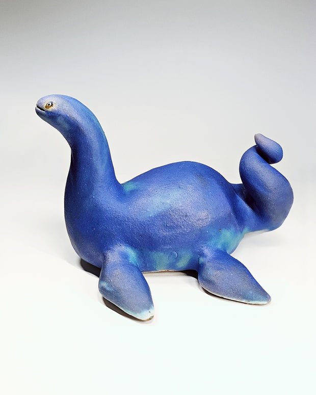 Ceramic sculpture of a sea monster akin to the Loch Ness Monster with bright blue glazing and a speckle finish.