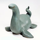 Ceramic sculpture of a sea monster akin to the Loch Ness Monster with a greenish blue glazing and a dotted finish.