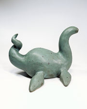 Ceramic sculpture of a sea monster akin to the Loch Ness Monster with a greenish blue glazing and a dotted finish.
