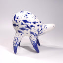 Ceramic sculpture of a white quadruped creature with blue glossy designs on its body of fish and coral, the fish swimming amongst bubbles.
