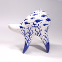 Ceramic sculpture of a white quadruped creature with blue glossy designs on its body of fish and coral, the fish swimming amongst bubbles.