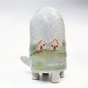 Ceramic sculpture of a turtle with a very tall shell, which has a landscape design on it of a grassy hill and small houses.