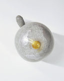 Ceramic sculpture of a turtle with a very tall shell, which has a landscape design on it of a grassy hill and small houses.