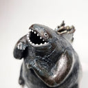 Ceramic Godzilla figure with a surface finishing akin to cooled magma, black with a subtle sheen. It has a very small, smooth head and a large plump body and back spikes.