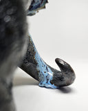 Ceramic Godzilla figure with a surface finishing akin to cooled magma, black with a subtle sheen. It has a very small, smooth head and a large plump body and back spikes.