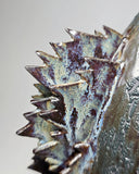 Ceramic Godzilla figure with a surface finishing akin to cooled magma, black with a subtle sheen. It has a very small, smooth head and a large plump body and back spikes.