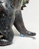 Close-up of a dinosaur ceramic figure, showing the detail on its tail.