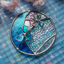 Circular stained glass artwork with flowers coming off of it.