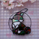 Stained glass hanging art of a Shiba Inu dog, silhouetted by its white markings and iridescent black coloring for its fur. 