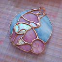 Stained glass hanging art of a Shiba Inu dog, silhouetted by its white markings and pink coloring for its fur. Background is a blue glass circle.