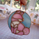 Stained glass hanging art of a Shiba Inu dog, silhouetted by its white markings and pink coloring for its fur. Background is a blue glass circle.