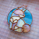 Stained glass hanging art of a Shiba Inu dog, silhouetted by its white markings and iridescent purplish green coloring for its fur. Background is a blue glass circle.