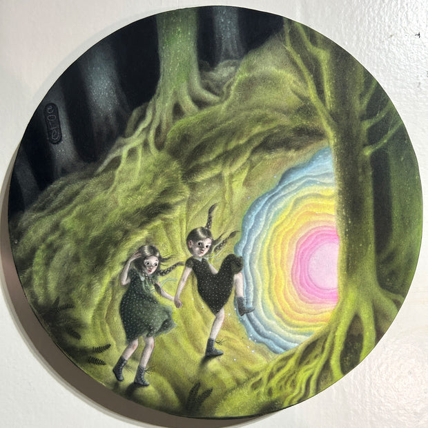 Illustration on round panel of a night forest setting, featuring a cave emitting a green glow and its entrance walls lined with blue, yellow and pink coloring. 2 girls in dresses and windblown hair walk towards the entrance. 
