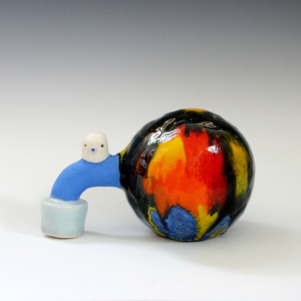 Sculpture of a large black sphere with orange, yellow and blue streaks. Coming out of it is a blue curved pipe shape, with a small white blob character on top. 