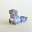 Ceramic figurine of a small tanuki raccoon with golden eyelids