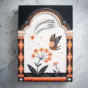 Black ink drawing with orange accent coloring on a stark white background of a butterfly landing on a blossoming flower. A falling star is in the sky and the piece is dramatically framed by decorated column motifs on each side.