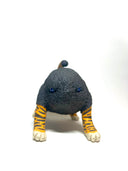 A small sculptural animal figure resembling a cat or tiger, with a dark charcoal textured body, orange-and-black striped legs and tail, and cream paws, photographed on a clean white studio background.
