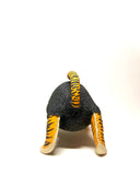 A small sculptural animal figure resembling a cat or tiger, with a dark charcoal textured body, orange-and-black striped legs and tail, and cream paws, photographed on a clean white studio background.